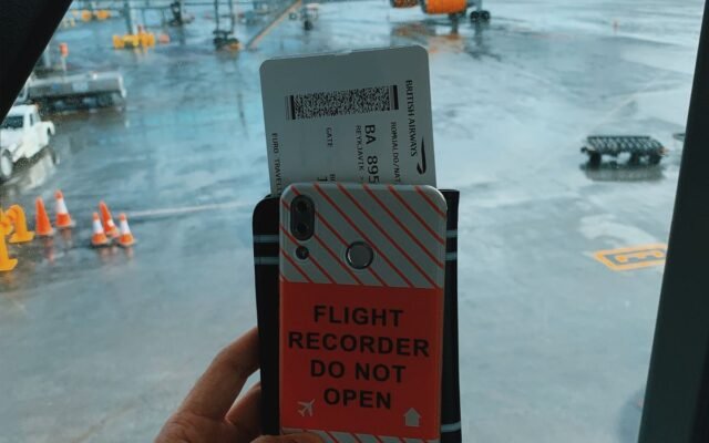 Traveler holding a boarding pass with a plane visible through the window at Keflavík Airport