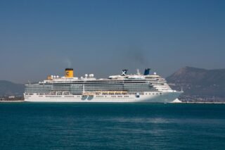 A majestic cruise ship sails near the scenic coastline of Corfu