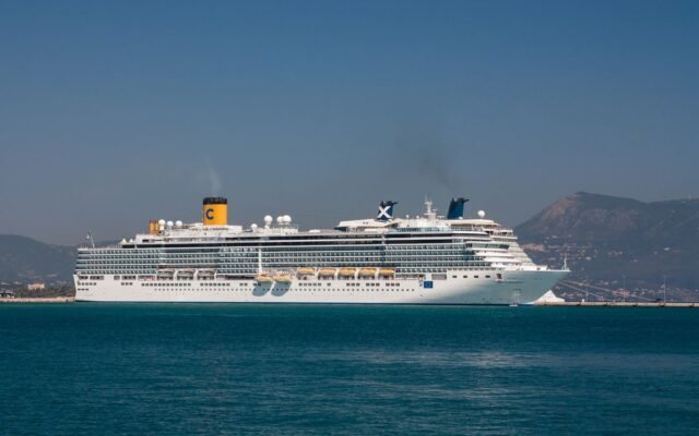 A majestic cruise ship sails near the scenic coastline of Corfu
