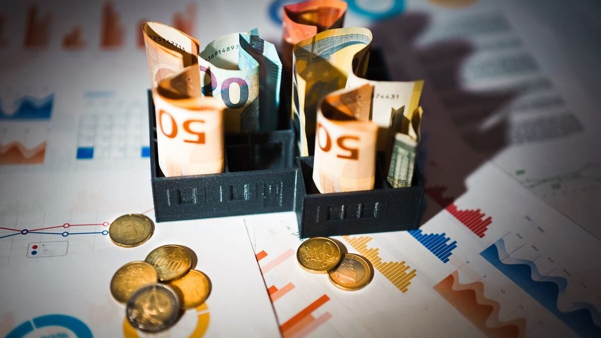 A close-up of euro banknotes and coins on top of financial charts symbolizing investment and economic analysis