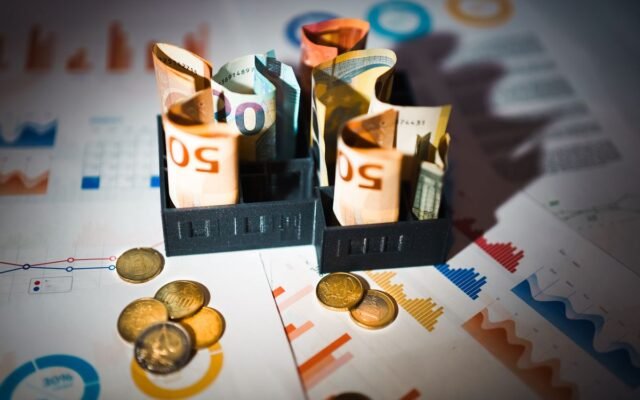 A close-up of euro banknotes and coins on top of financial charts symbolizing investment and economic analysis