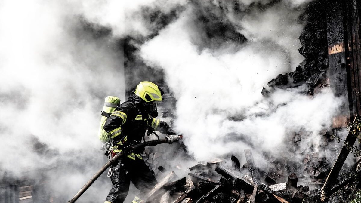 A determined firefighter fights a raging fire amidst thick smoke