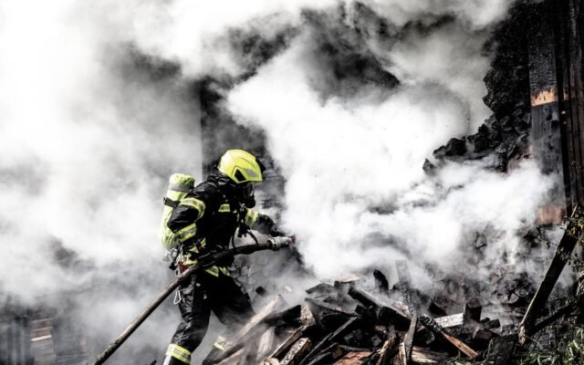A determined firefighter fights a raging fire amidst thick smoke