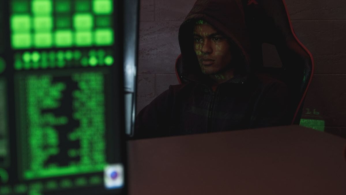 Hooded programmer intensely focused on computer screen