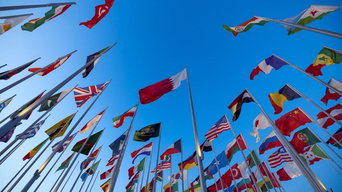 International flags waving against a clear blue sky in Doha