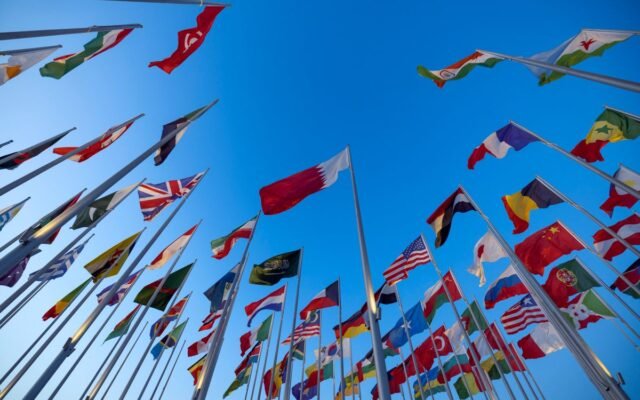 International flags waving against a clear blue sky in Doha