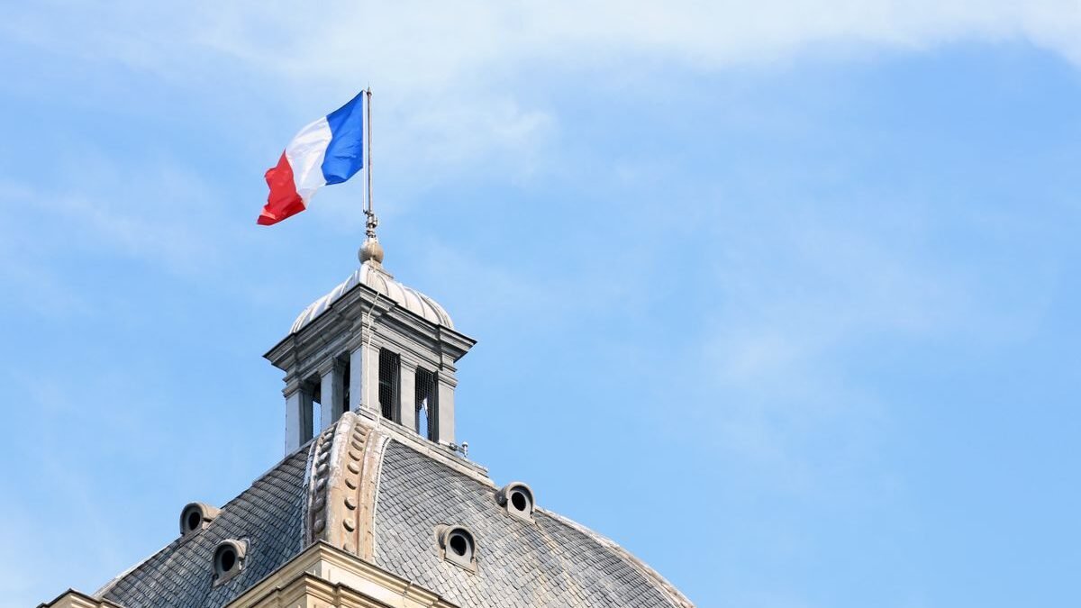 The French flag waves atop the dome of historic architecture in Paris
