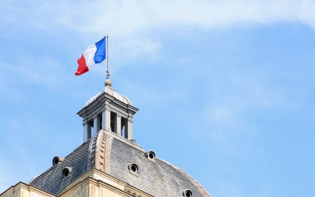 The French flag waves atop the dome of historic architecture in Paris