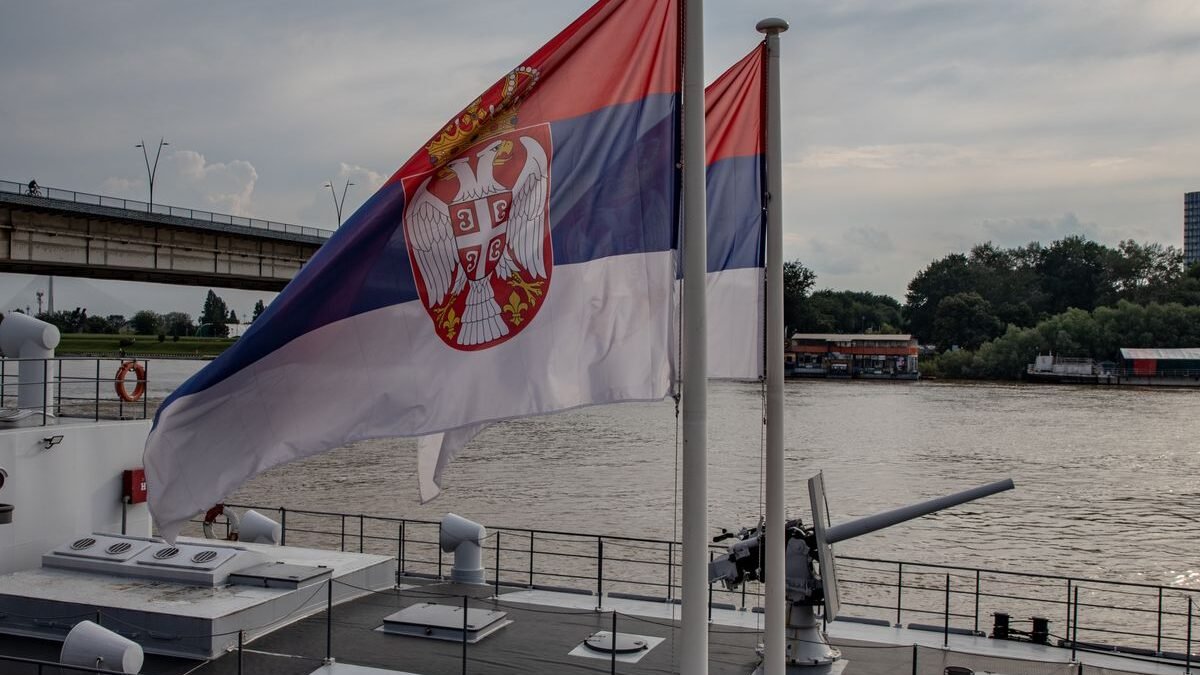 Serbian flag seen on a riverboat under a cloudy sky