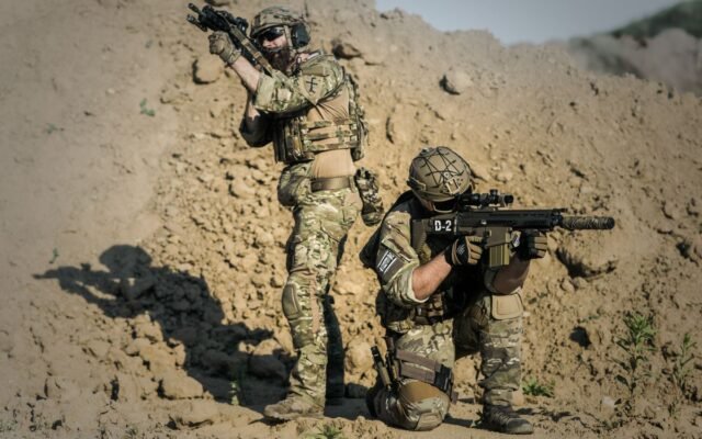 Two soldiers in camo engage in tactical training in a desert environment