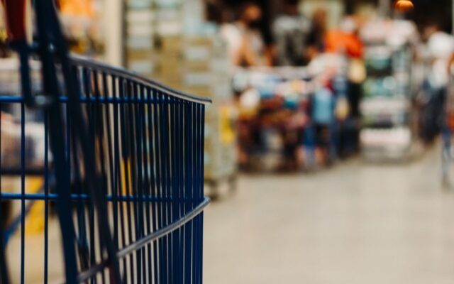 Shopping cart in a busy supermarket aisle with blurred background