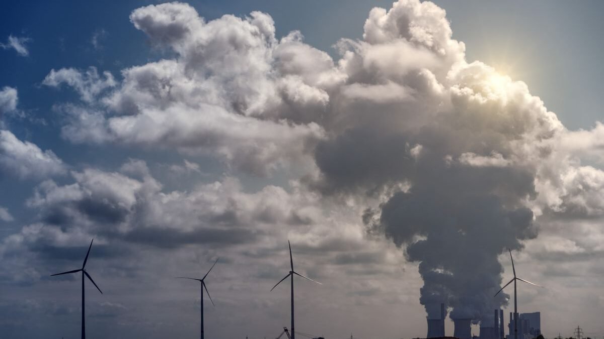 Wind turbines and a power plant under dramatic cumulus clouds in a rural landscape