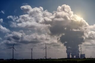 Wind turbines and a power plant under dramatic cumulus clouds in a rural landscape