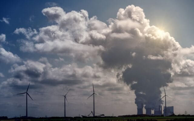 Wind turbines and a power plant under dramatic cumulus clouds in a rural landscape